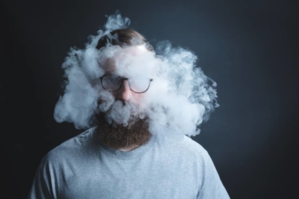 Man clouded by secondhand smoke against dark background