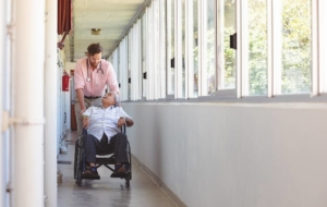 Nurse pushing senior patient in wheelchair inside