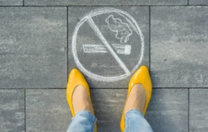Woman in yellow heels stands by no smoking sign on pavement