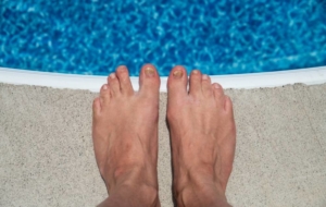Mans feet by pool deck outside