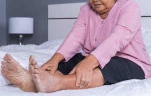 Woman sitting on bed with leg pain from PAD