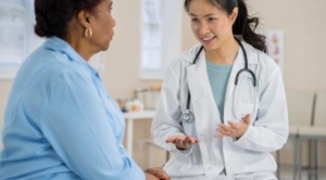 Older woman talking to friendly doctor about leg numbness