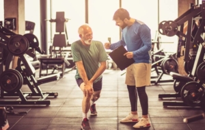 Senior man exercising at gym with professional trainer