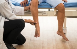 Doctor examining mens legs on clinic table