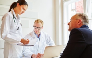 Two doctors talking to senior man about treatment options