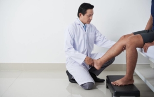 Doctor examining mans leg with pad