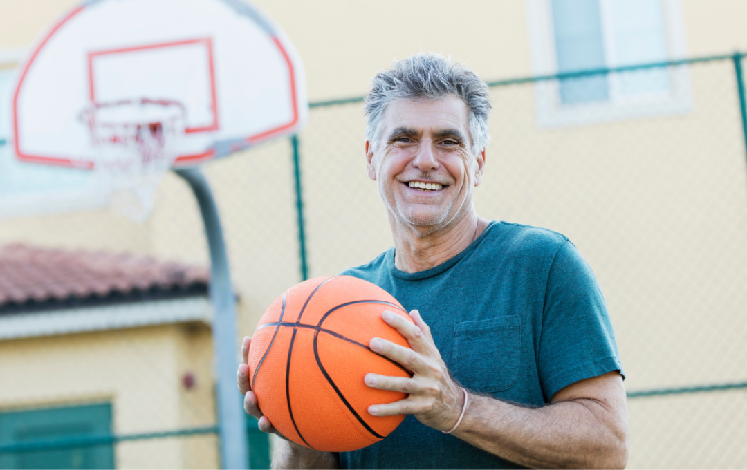 Middle aged male patient reaps the benefits of angioplasty and can now play basketball with no pain in his legs.