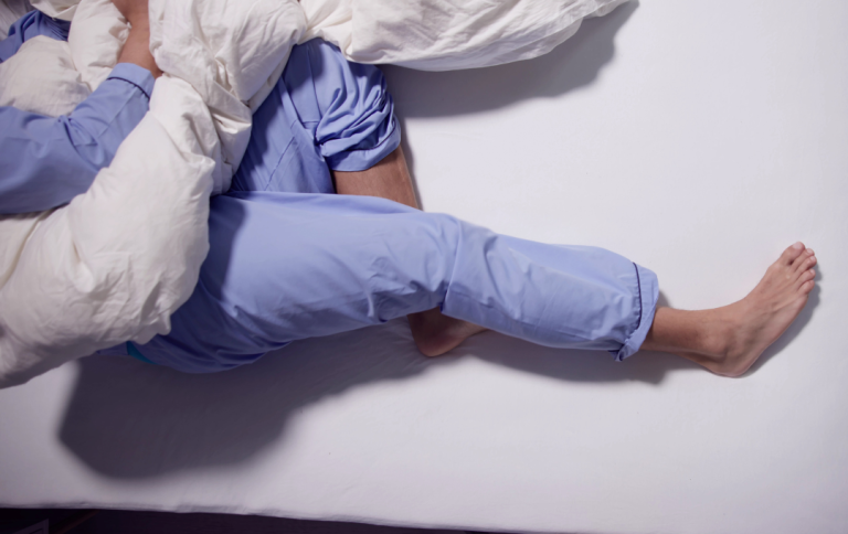 Man in bed suffering from restless leg syndrome at night.