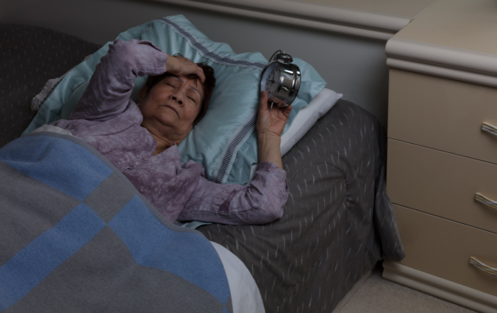 A woman laying in bed late at night with restless legs.