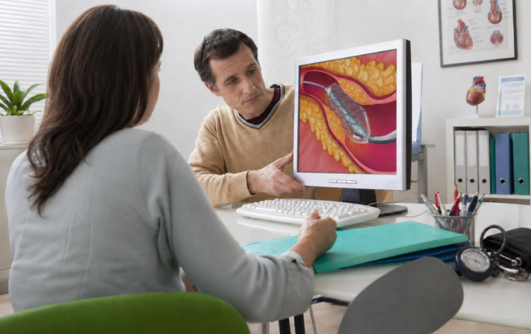 A vascular specialist shows a male patient how an angioplasty with stent works.