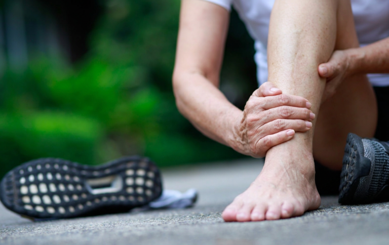 Woman sitting in the middle of the road holding her foot to ease numbness.
