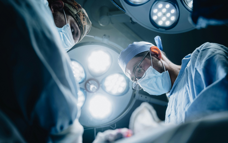 Vascular surgeon performing bypass surgery to remove PAD blockage from patient's legs.